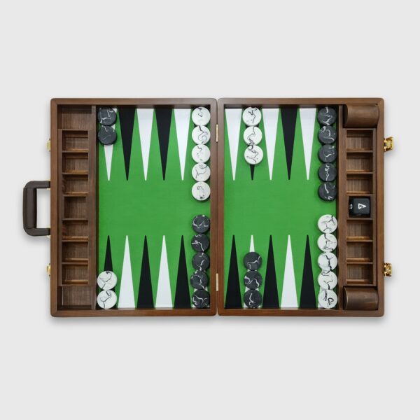 A tournament-sized Monte Carlo backgammon board with green and brown playing surfaces, accompanied by a set of black and white checkers, a doubling cube, and dice cups, with the board's case partially visible.